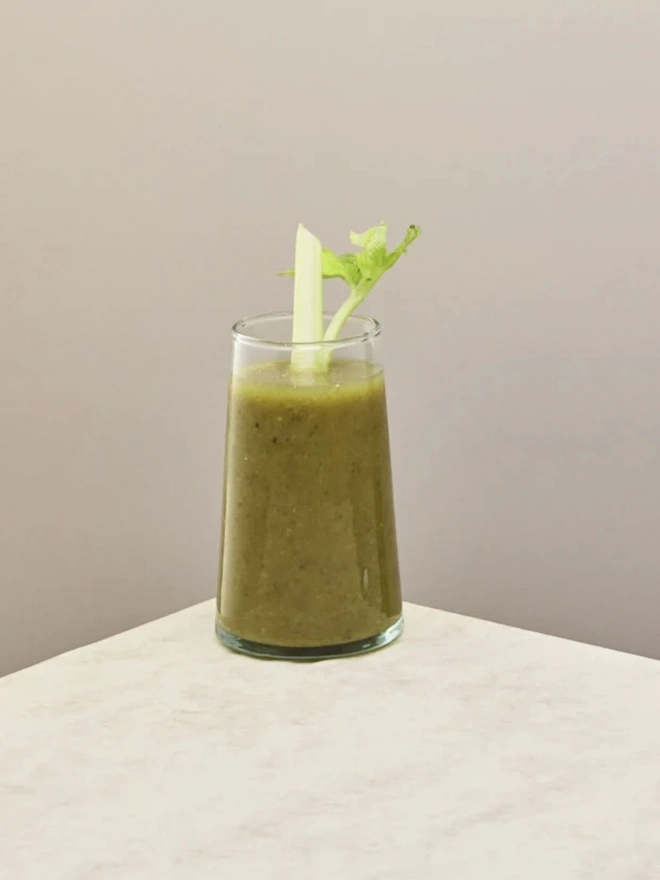 Highball Glasses (Set Of 1 Or 4), a highball glass sitting on a plain counter top against a white backdrop. It is filled with a soft drink. 