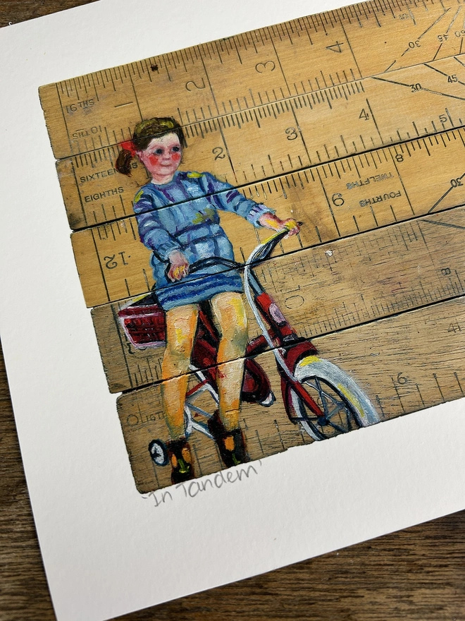 little girl sitting on a retro bike painted onto vintage school rulers