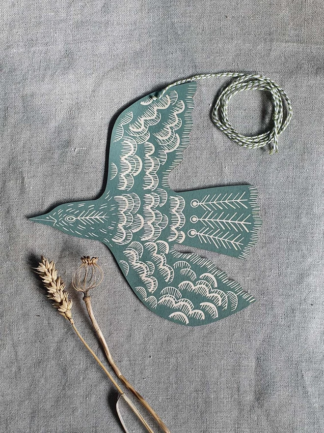 Hanging wooden hand printed bird decoration in a green colour.
