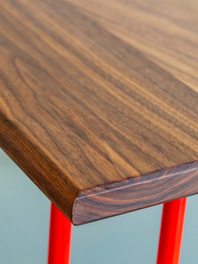 corner view of a hairpin leg table with walnut top and red legs