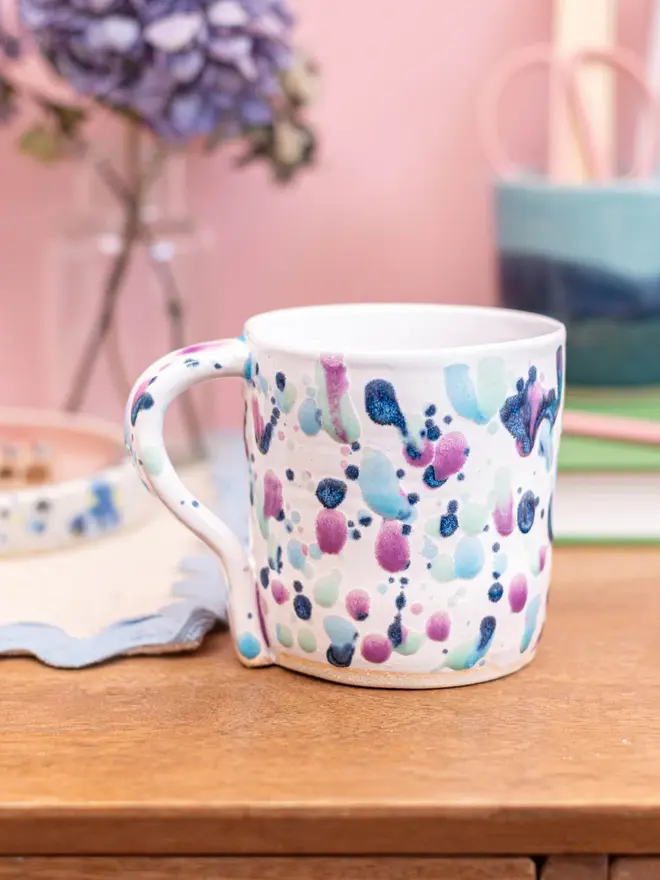 Sweetpea Standard Mug, a colourful mug on a wooden desk accompanied by other desk accessories. 