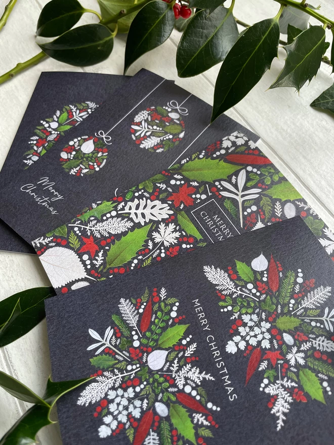 Pack of 4 Unique Christmas Cards with Pressed Winter Leaf Designs - Laying on White Background - Surrounded by Holly Sprigs