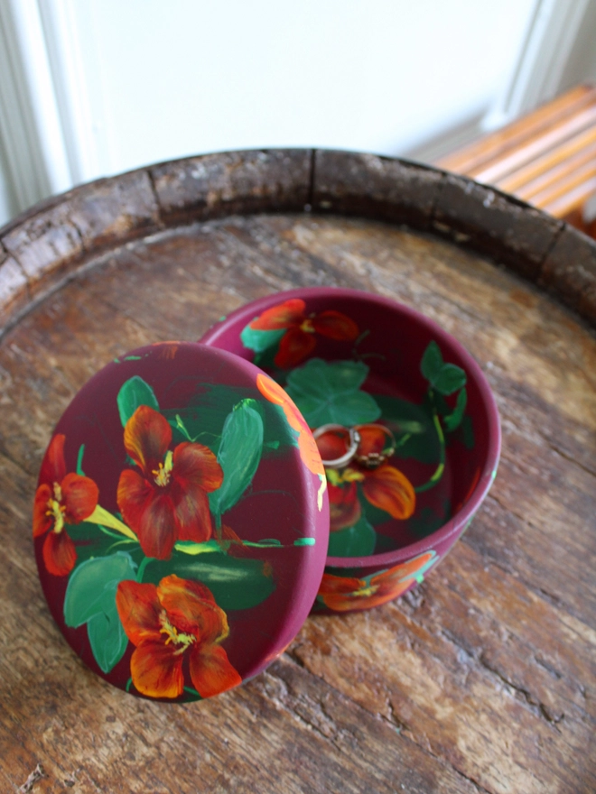 hand painted floral ceramic round box background painted in a deep maroon adorned in fiery Nasturtium flowers