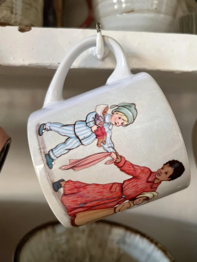 a photo of a cosy childrens mug featuring a little boy in pjs heading to bed drawn in a traditional story book style by mandy sutcliffe