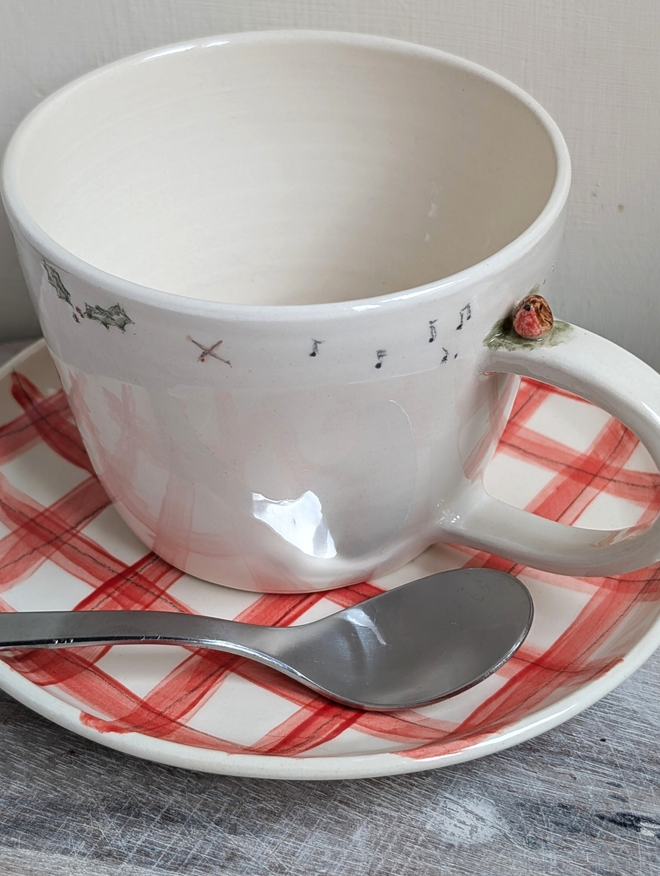 ceramic cup with a tiny pottery robin on the handle with musical notes and tiny bird prints on a red gingham pottery plate