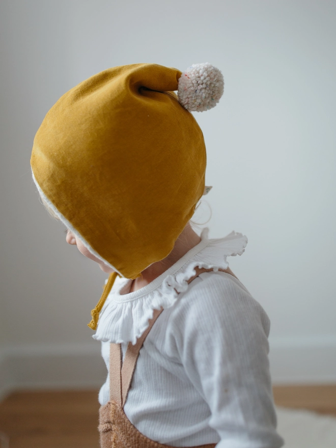 Baby wearing her winter pixie hat in mustard corduroy