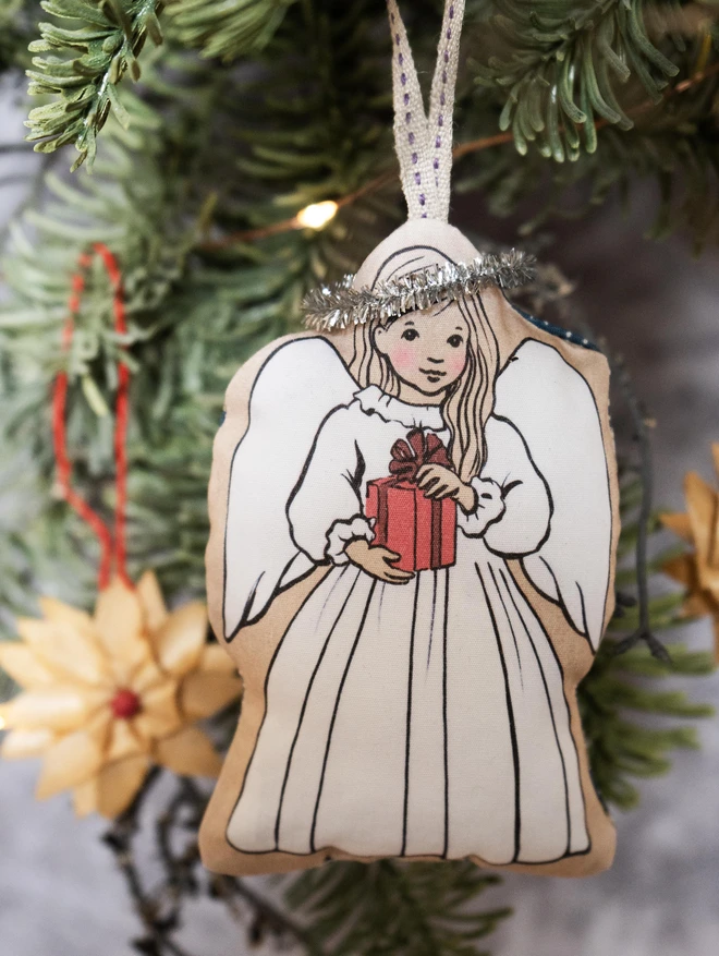 sweet little christmas angel christmas tree decoration little girl has long blonde hair holding a christmas prsent