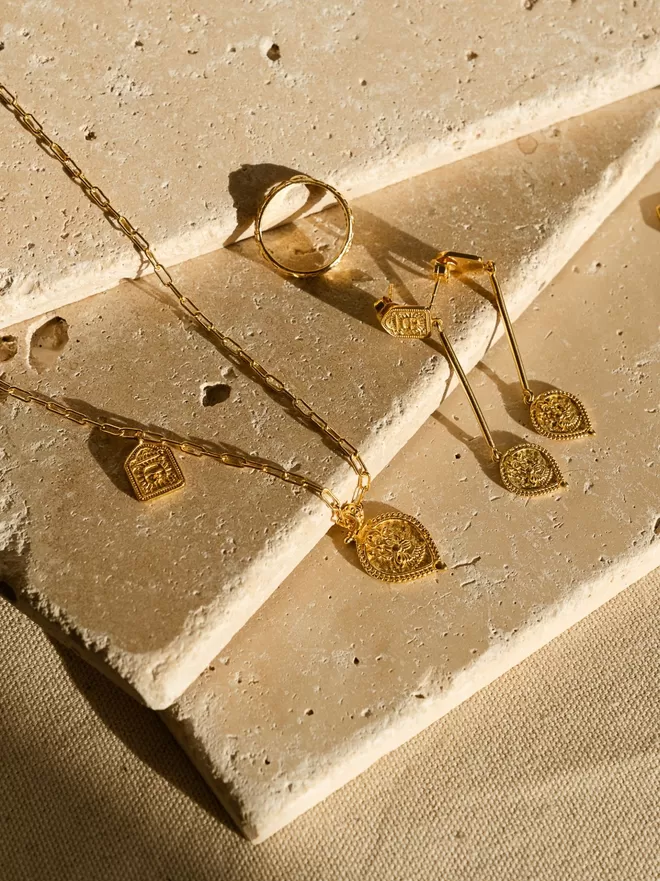 Double charm pendant featuring Hindu god Ganesh with matching teardrop earrings featuring Ganesh on stone slab background