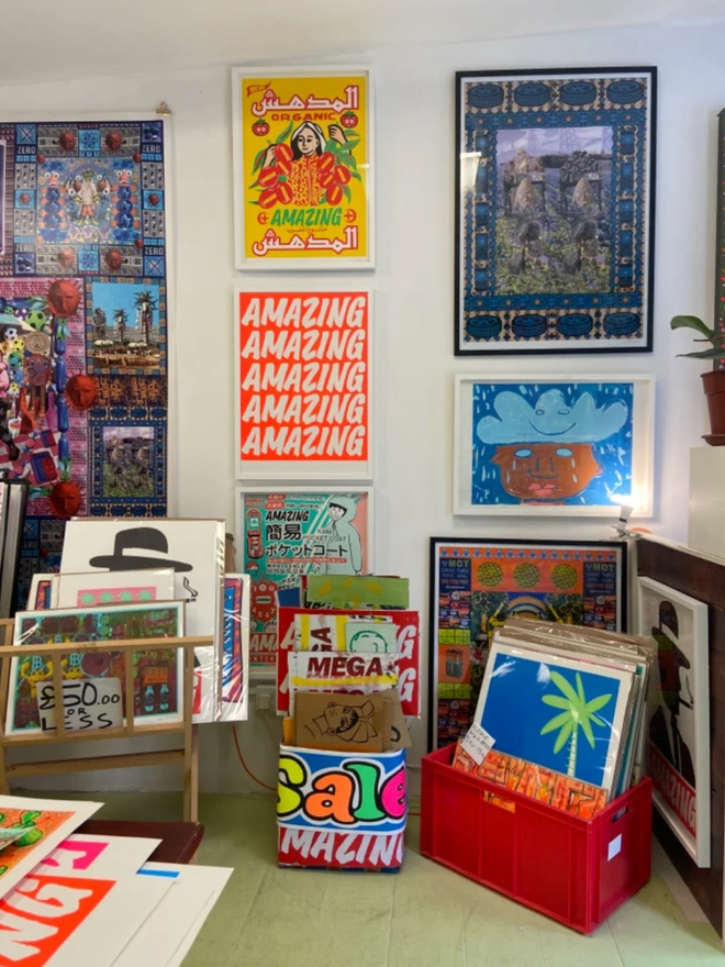 Fluoro Amazing Print. A vibrant orange background with AMAZING written five times, hung against a wall.