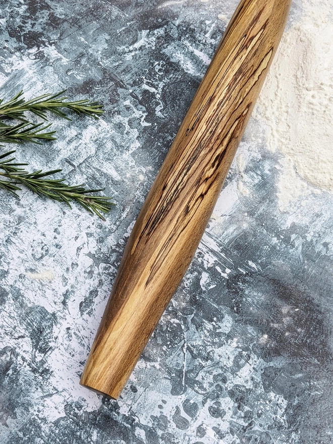 A highlight shot of a hand made rolling pin in Spalted Beech by Something From The Turnery, the picture is focussed another side of the rolling pin which boasts dramatic , all natural grain patterns.
