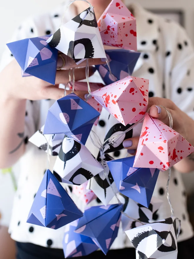 woman holding colourful set of origami fairy lights
