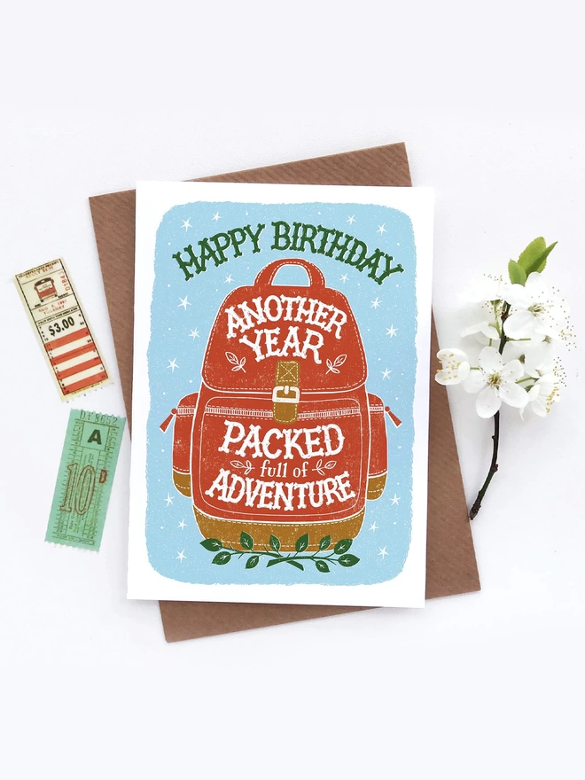 Red backpack birthday card with flowers and tickets