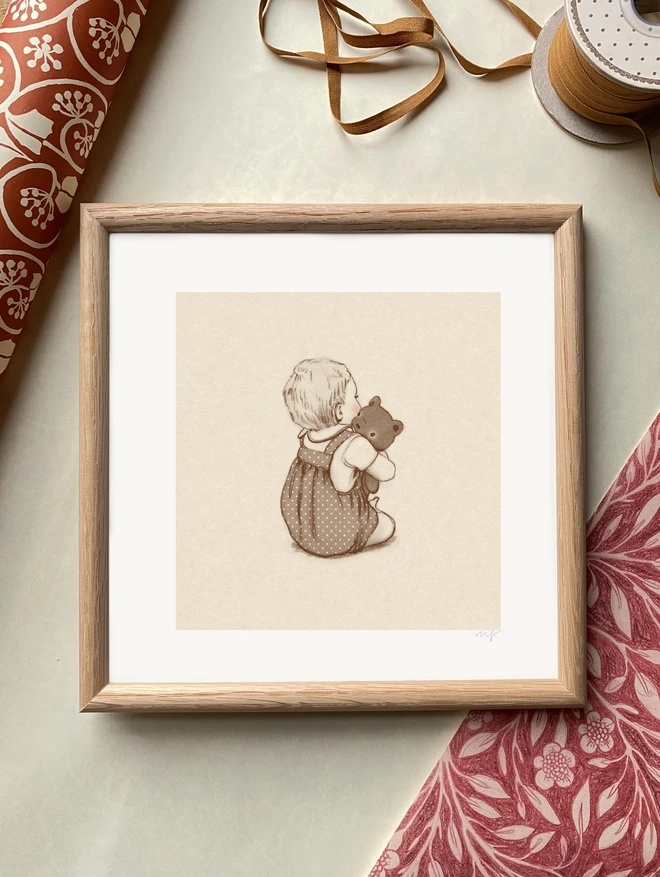 a photography of a framed sepia drawing of a baby sat up hugging a teddy. drawn in a traditional story book style in sepia cream with rosy pink cheeks