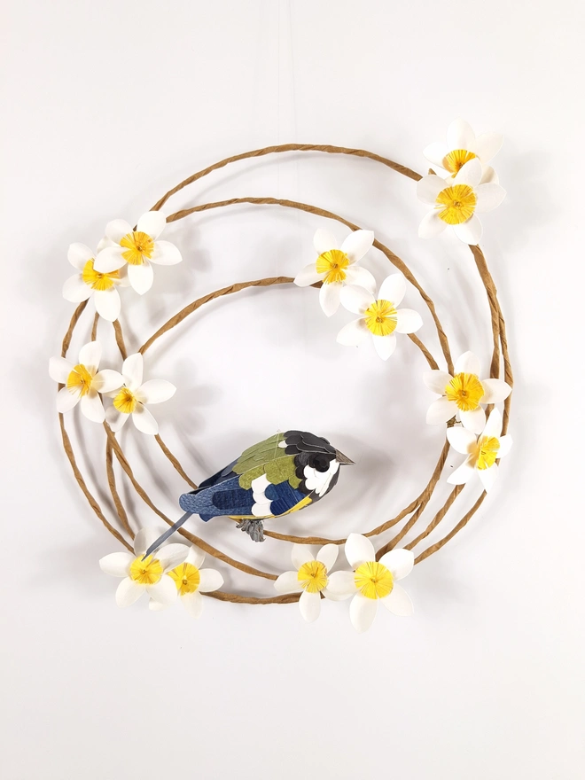 handmade paper sculpture of a great tit bird perched on a spring wreath of white paper flowers