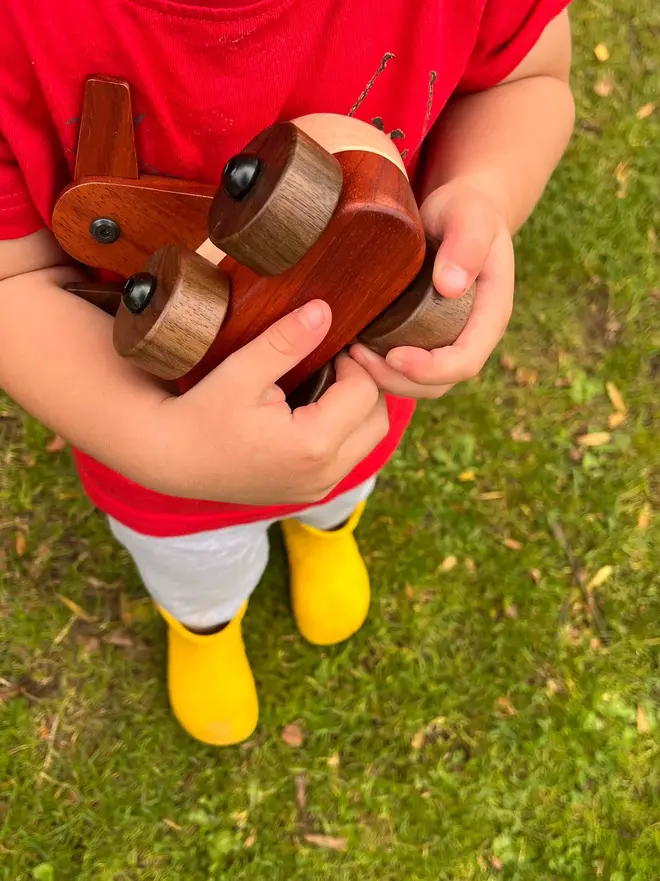 Walnut & Padauk Aeroplane Wood Heirloom Toy, being held. 
