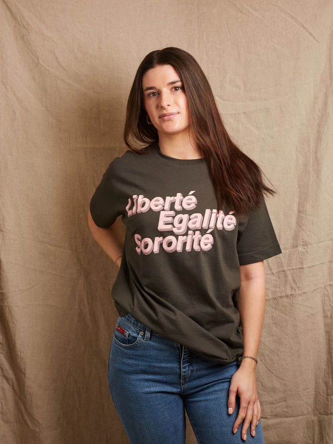 Model is wearing a charcoal grey cotton t-shirt with the slogan Liberté, Egalité, Sororité in pale pink written on the front