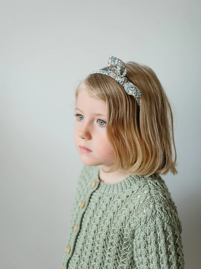 Little girl in Liberty Alice Band and green cardigan