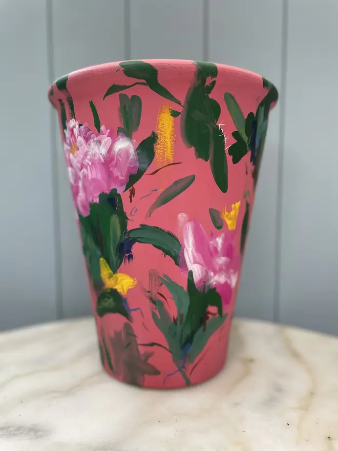 Unique hand-painted terracotta pot featuring pink peonies on a red background