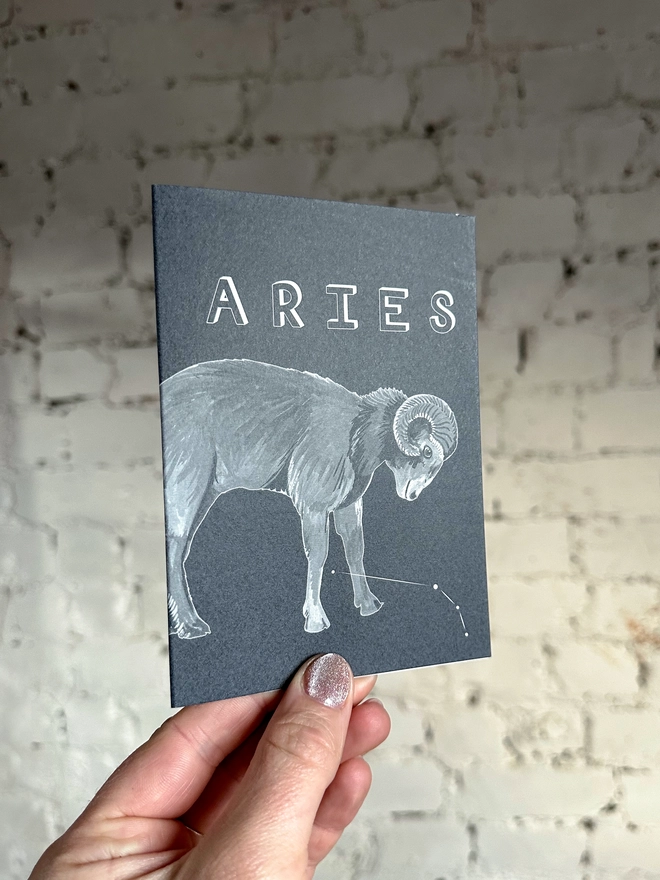 a greetings card featuring a greyscale illustration of a zodiac style ram with the text “ARIES”