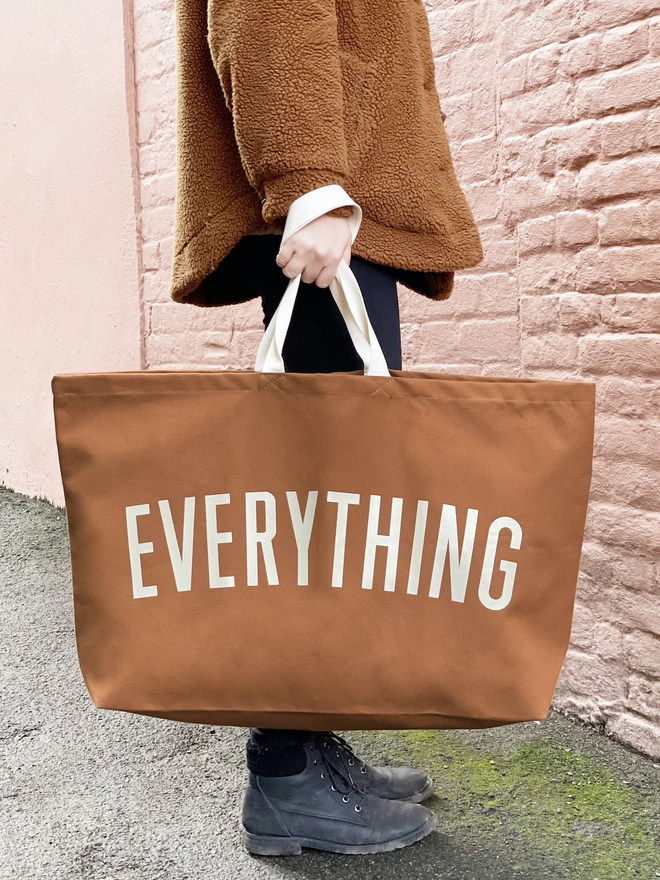 Model holding the Everything oversized tote bag in tan