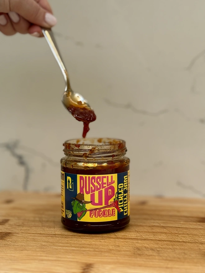 father's day pickles - spice set. a jar of chilli jam being spooned out.