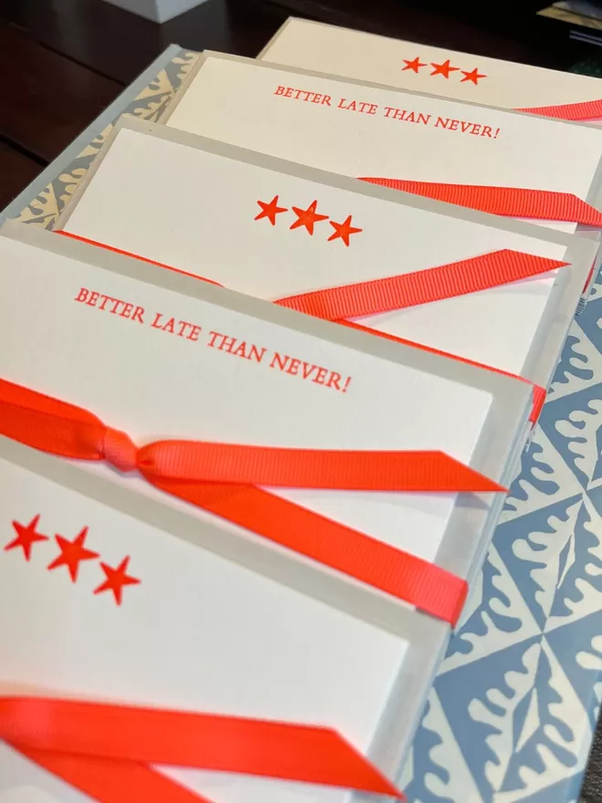 The Better Late Than Never cards in orange by South London Letterpress seen with neon orange star cards.