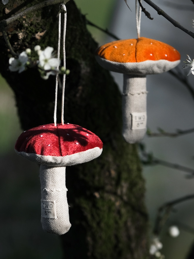 Velvet toadstool decorations hanging from a tree with blossom