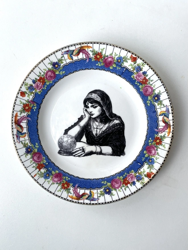 a vintage ornate plate with a pink floral border detail, in the centre i have printed a vintage black and white illustration of a pretty fortune teller reading a crystal ball