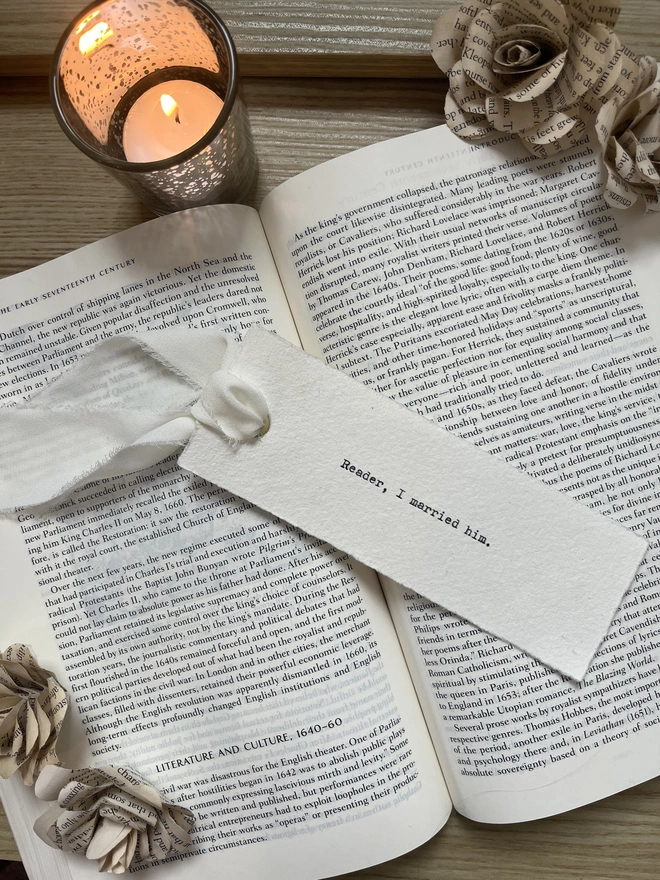 Chiffon ribbon tied through a handmade cotton rag paper bookmark with deckled edges, featuring a custom quote typed in black ink with a vintage antique typewriter.