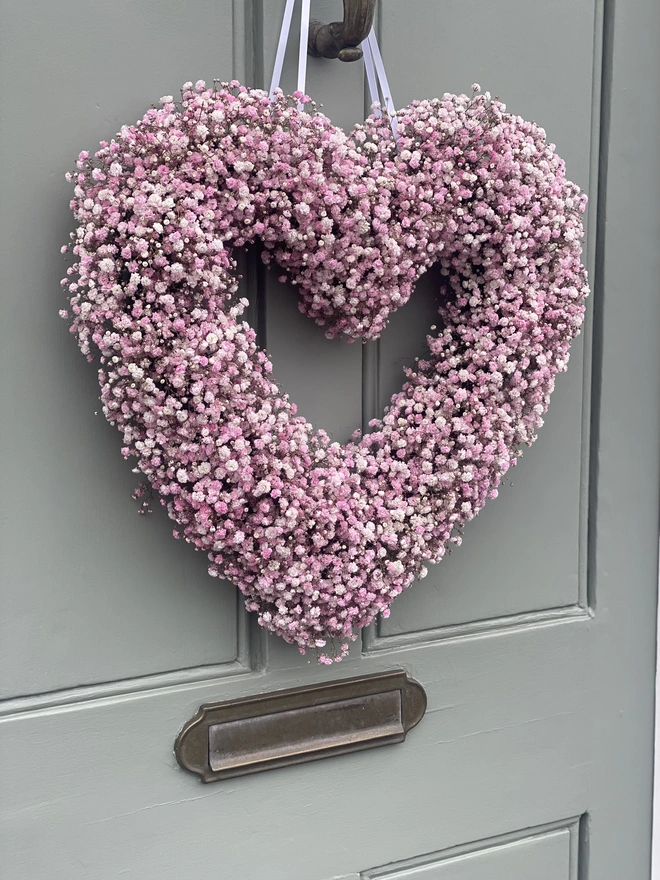 Light Pink Gypsophilia Heart Wreath hanging against a grey door