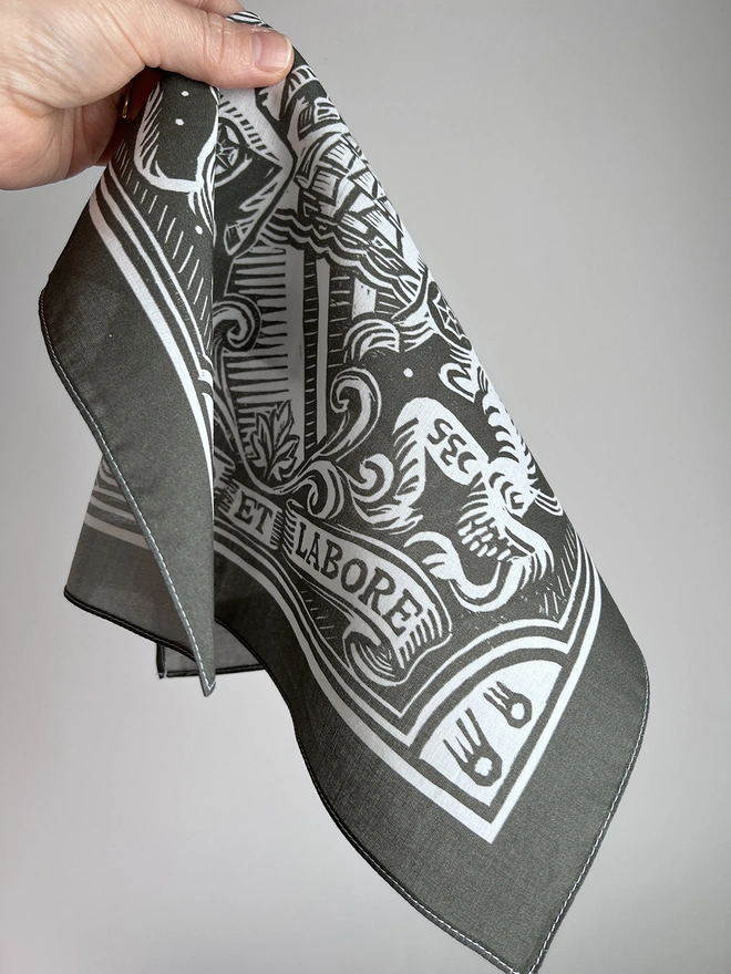 A scrunched up Mr.PS grey Manchester Heraldic Handkerchief pocket square in a hand