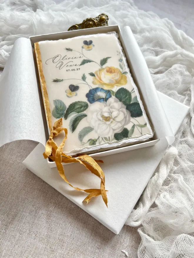 Floral vellum and handmade paper blank vow booklets tied with faux silk ribbon for an authentic old world charm. Show in a luxury gift box with tissue paper