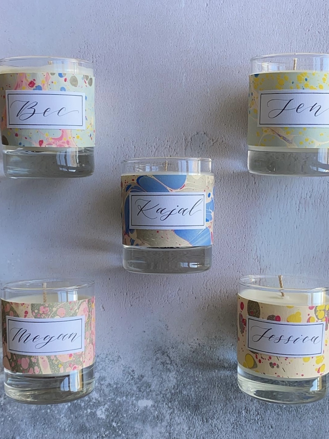 Hand Poured Scented Candle With Personalised Marbled Label seen with a flower.