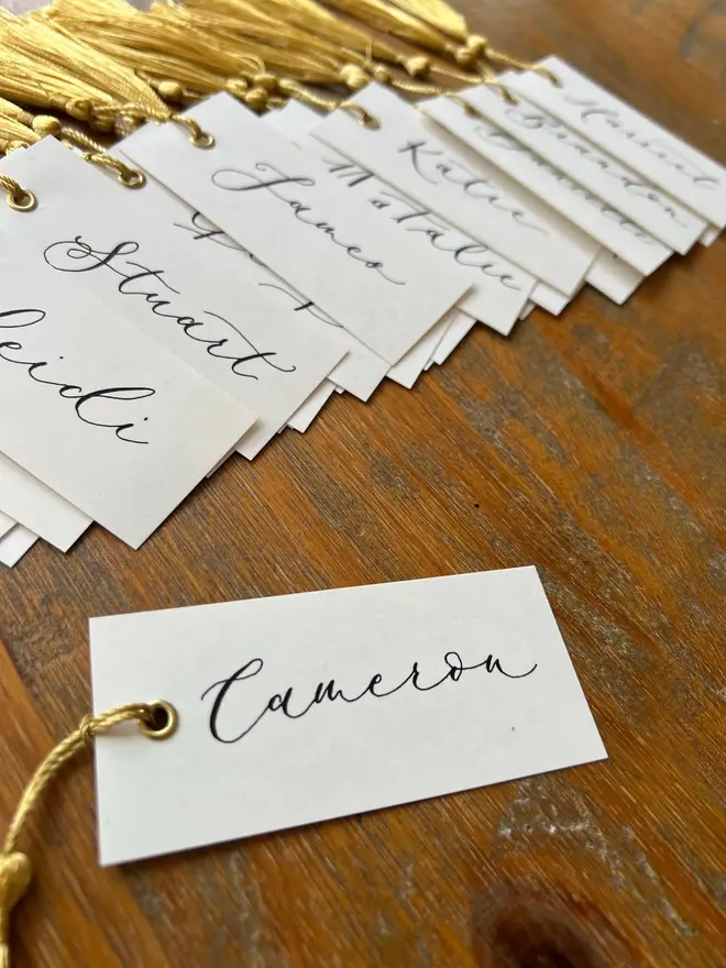 Personalised Calligraphy Wedding White Place Cards, white place cards with ivory and gold tassel. 