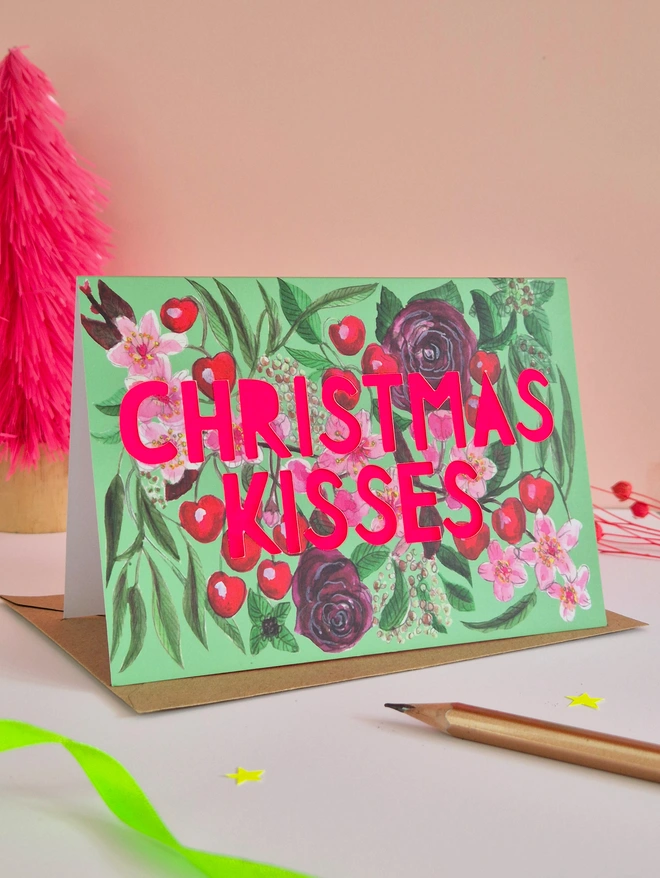 Cherry illustration Card with Christmas kisses in paper cut text with neon pink backing paper