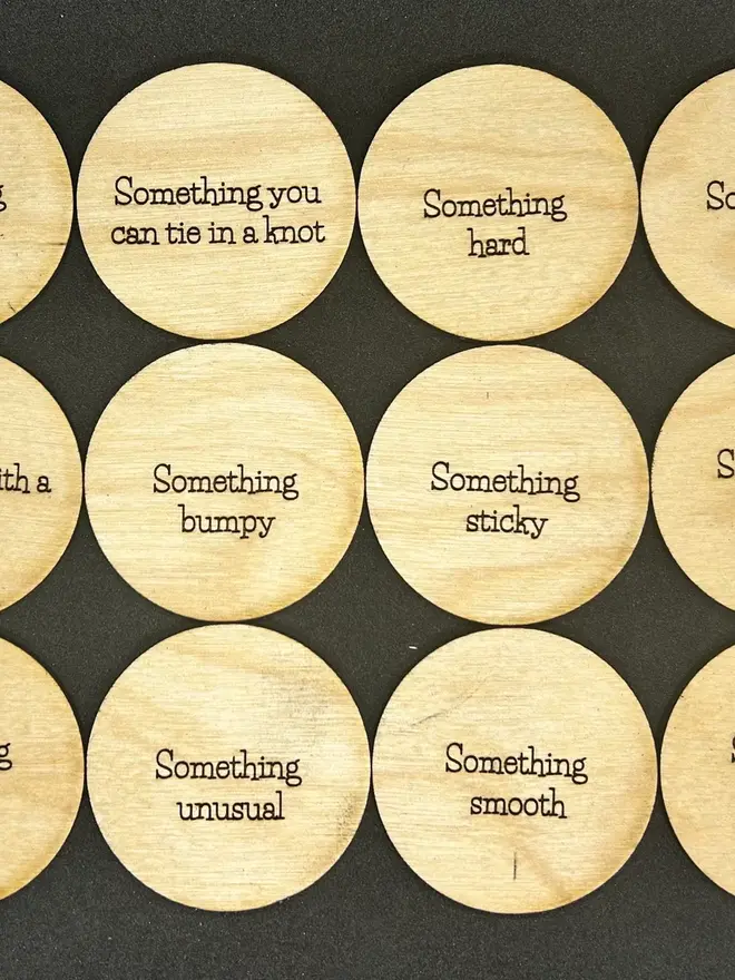 Wooden Nature Trail scavenger and mindfulness discs engraved with prompts and nature illustrations displayed on a table. 