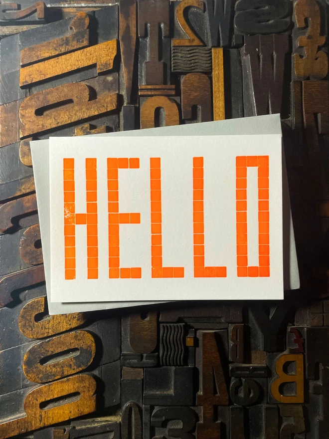 Letterpress HELLO postcard printed from a grid of square wooden type blocks in fluorescent yellow ink, deeply impressed on thick 350gsm Colorplan Pristine White card.