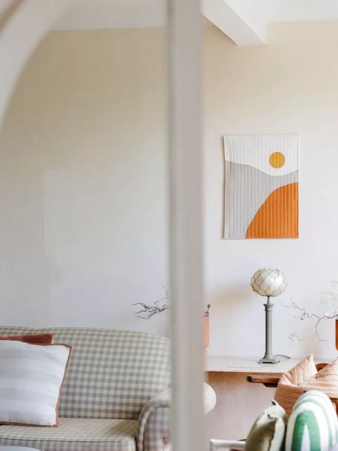 Sunrise Quilt Hanging On a White Wall In a Living Room