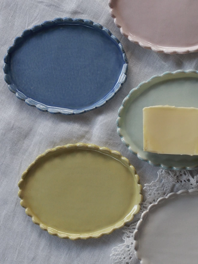 a variety of butter dishes in blue, yellow, pink, white and green