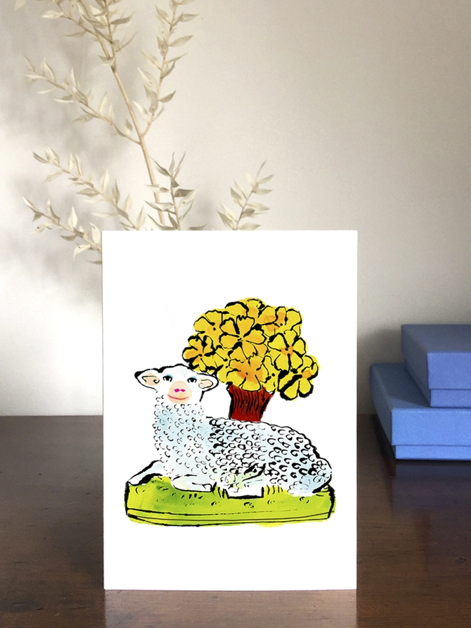 A greeting card featuring a springtime lamb with some flowers