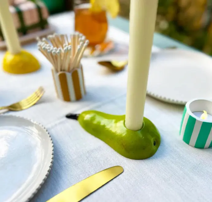 Pear Candlestick Holder. Candle placed in green pear candlestick holders displayed on a table alongside matchstick holder. 