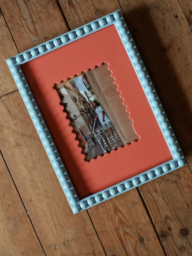 peach shaped frame mount with photograph, in blue bobbin frame