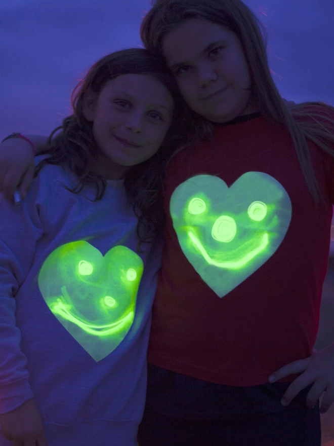Two girls standing together in dark with glow in the dark heart tshirts on