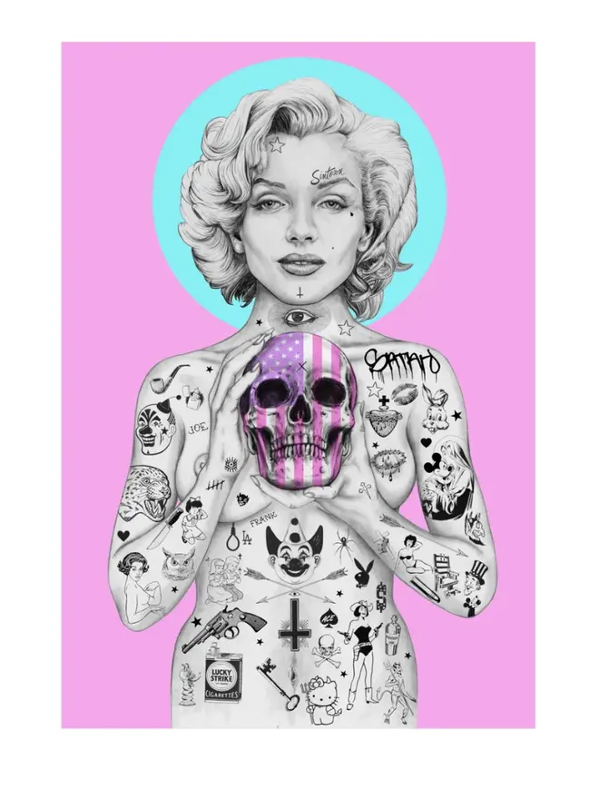 Tattooed portrait of Marilyn Monroe holding a pink skull with an American flag pattern against a pink background with a blue halo.
