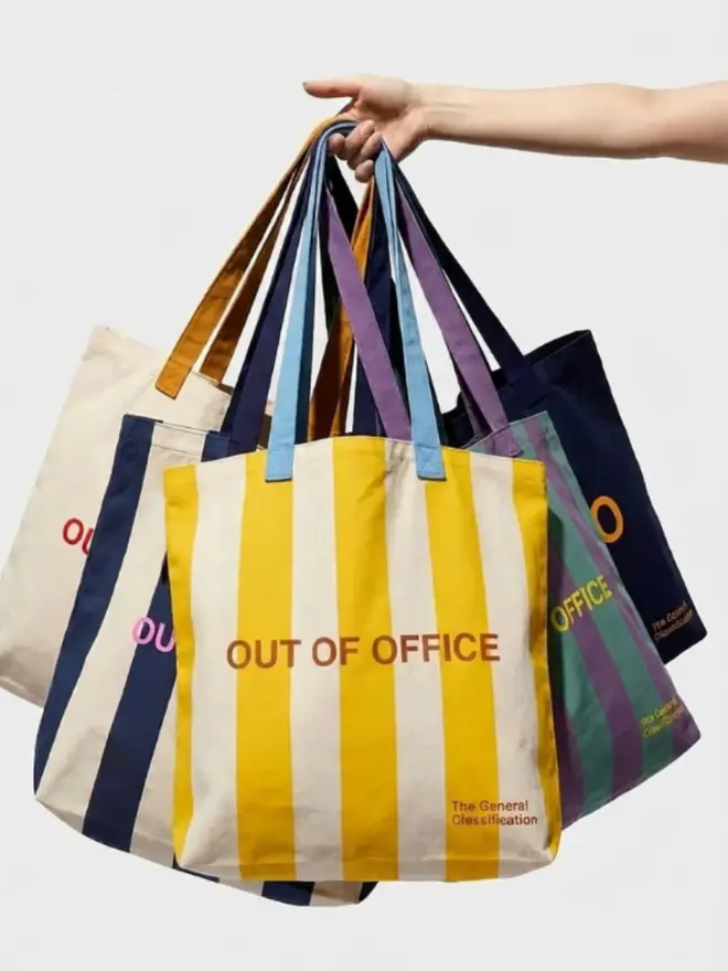 Out Of Office Tote Bags, being held by a woman against a white background. 