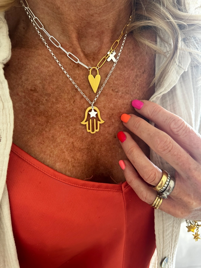 model wears gold hamso hand charm on sterling silver chain with silver mini star