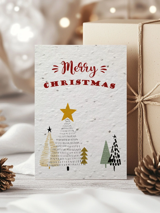 Christmas card with Christmas trees and 'Merry Christmas' on surrounded by presents in a Christmas scene