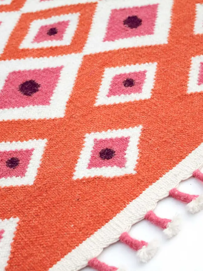 Evil Eye Flatweave Rug, a colourful rug on a plain surface. 