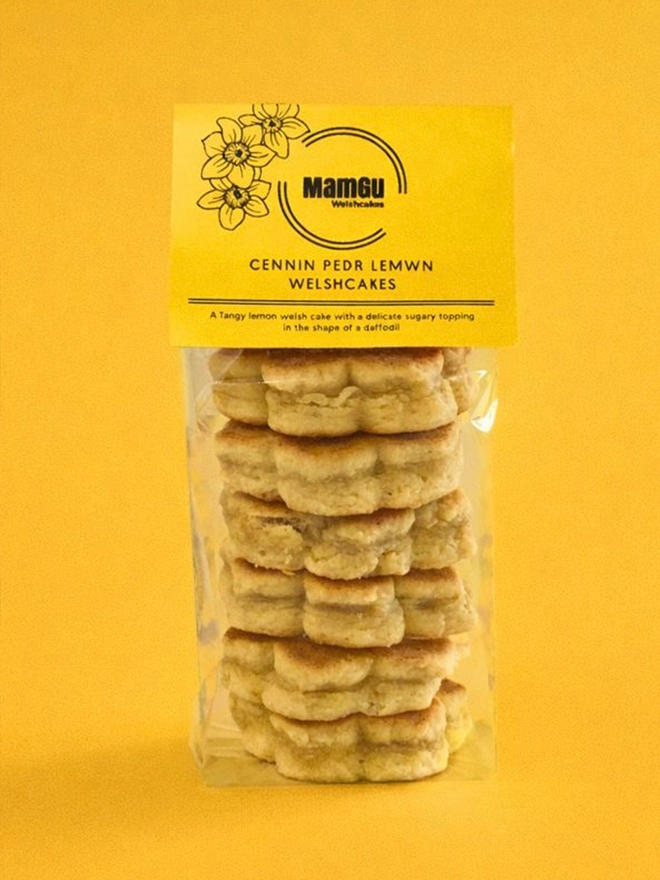 6 Lemon Welsh Cakes in the shape of daffodils with a MamGu Welshcakes yellow tag and a yellow studio background
