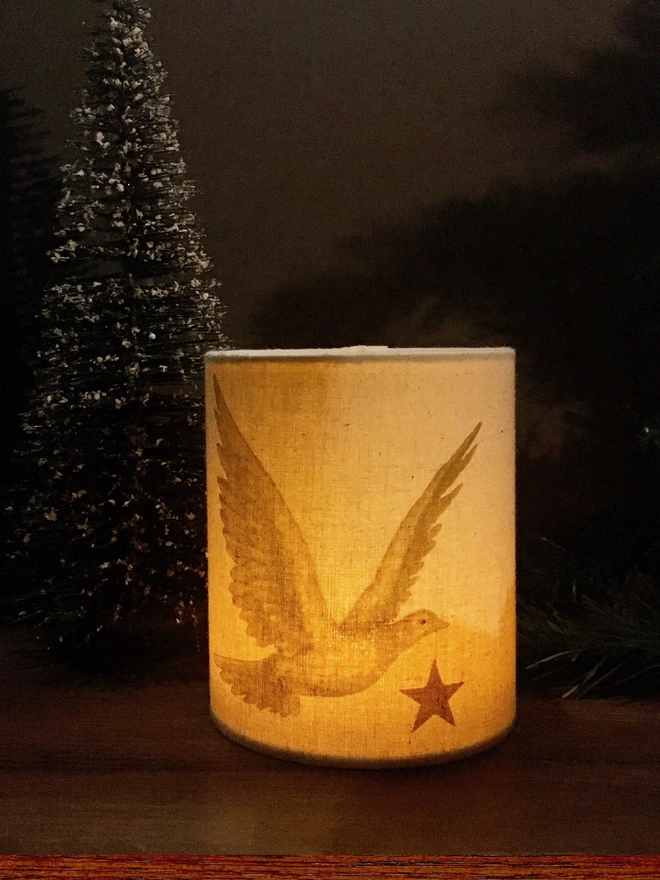 A lit tealight holder with dove and star